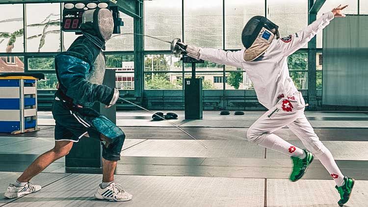 Fechtschüler in weiss setzt gegen seinen Lehrer einen Treffer. 