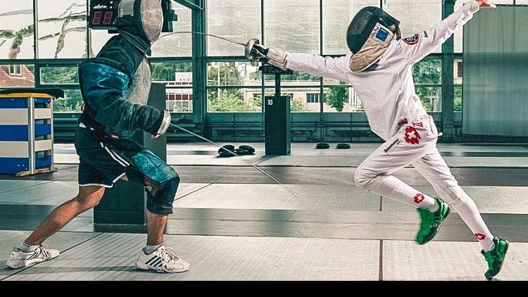 Fechtschüler in weiss setzt gegen seinen Lehrer einen Treffer. 